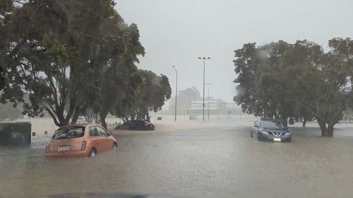 Cars are seen in a flooded street during heavy rainfall in Auckland, New Zealand 27 January 2023, in this screen grab obtained from a social media video. @MonteChristoNZ/via Reuters/File Photo