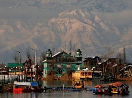 People row their boats in the waters of Dal Lake with the backdrop of snow-covered mountains after a snowfall in Srinagar | Reuters file photo/Danish Ismail