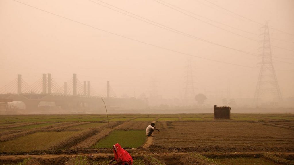 File photo of farmers working amidst smog in a field on the bank of the Yamuna river in New Delhi, India, on 8 November, 2022 | Reuters