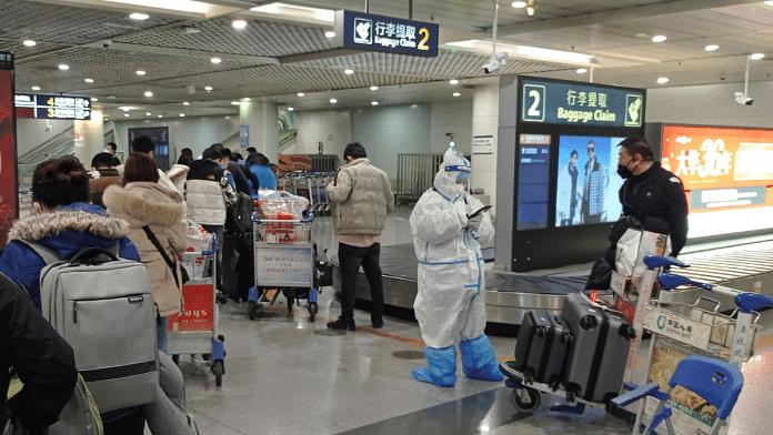 Passengers arriving on international flights wait in line next to a staff member wearing personal protective equipment (PPE) at the airport in Chengdu, China 6 January, 2023 | Reuters Photo
