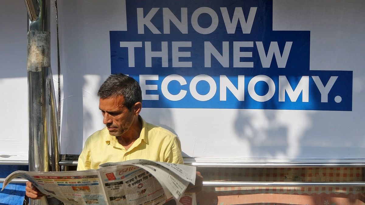 economy A man reads a newspaper as he waits for public transport at a bus stop in Mumbai | Reuters file photo