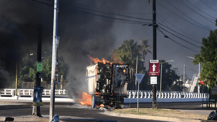 A burning vehicle is seen blocking a road after drug lord Ovidio Guzman's capture in Culiacan, Sinaloa, Mexico | Revista Espejo/Leo Espinoza/Handout via REUTERS