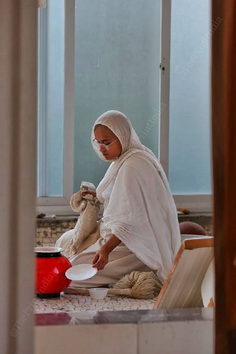 Sadhvi Nisangpragnya Shriji, 22, removes the lid of her water container — one of the few belongings that Jain monks and nuns keep with them | Praveen Jain | ThePrint
