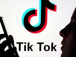 A person holds a smartphone as Tik Tok logo is displayed behind in this picture illustration | File Photo: Reuters