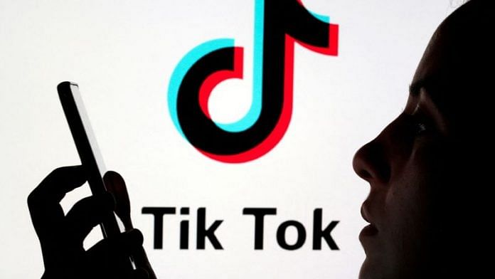 A person holds a smartphone as Tik Tok logo is displayed behind in this picture illustration | File Photo: Reuters