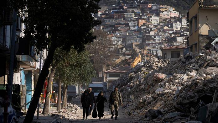 Turkish serviceman walks along a street with two women in the aftermath of a deadly earthquake in Antakya, Turkey, on 16 February 2023 | Reuters