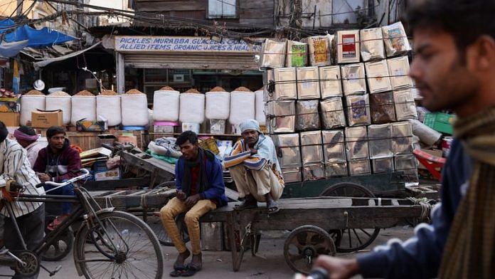 Workers sit on a cart at a wholesale market in the old quarters of Delhi on 7 December, 2022 | Reuters
