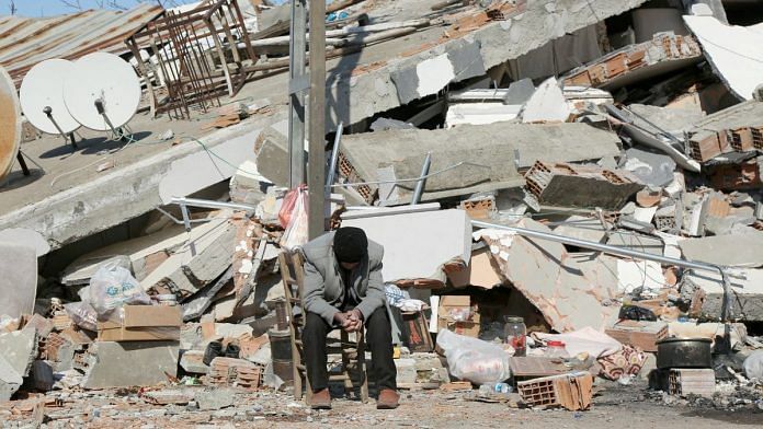 Seho Uyan, who survived a deadly earthquake, but lost his four relatives, sits in front of a collapsed building in Adiyaman, Turkey 11 February 2023 | Reuters/Sertac Kayar