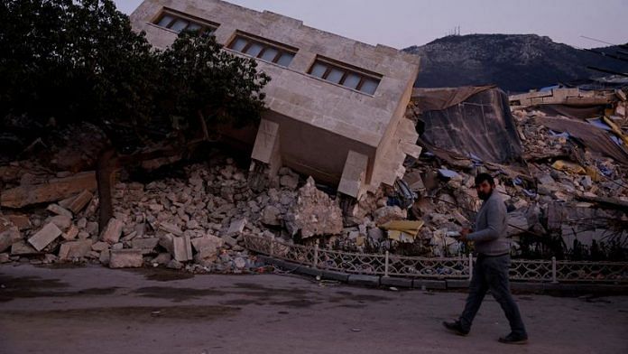 A man walks by a collapsed building and rubble, in the aftermath of a deadly earthquake, in Antakya, Hatay province, Turkey on 21 February, 2023 | Reuters