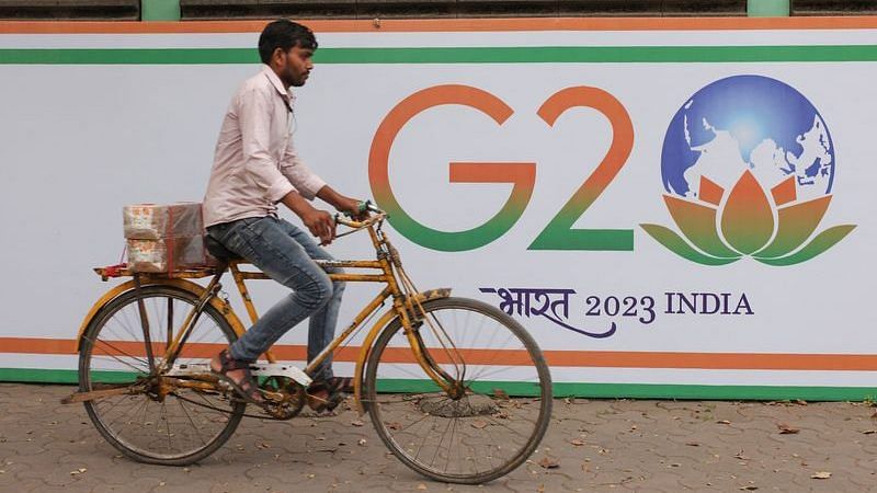 A man rides a bicycle past the hoarding of India's G20 presidency, on a street in Mumbai on 15 December, 2022 | Reuters