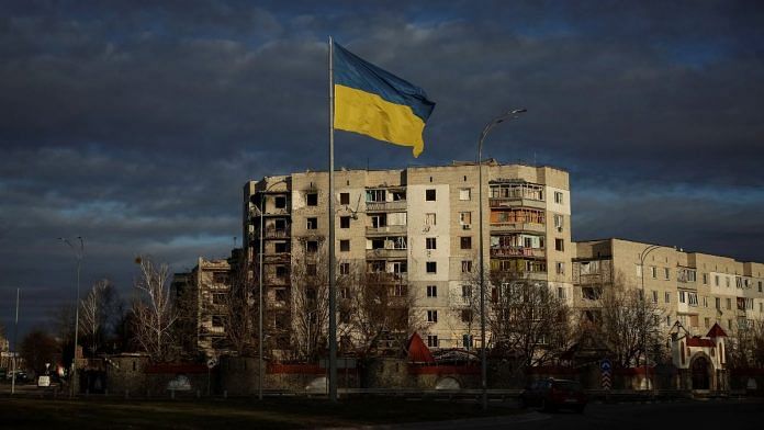 A Ukrainian national flag flutters near the buildings destroyed by Russian military strike, amid Russia's invasion of Ukraine, in the town of Borodianka, in Kyiv region, Ukraine 15 February 2023 | Reuters/Gleb Garanich