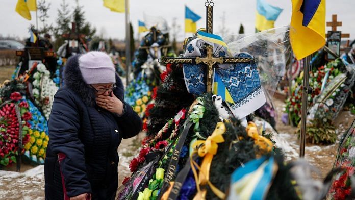 Mariia reacts near the grave of her son Vasyl Kurbet, Ukrainian service member killed in a fight against Russian troops, at a cemetery in Bucha, Ukraine, on 24 February 2023 | Reuters