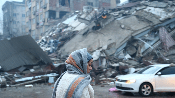 A woman stands near a collapsed building after an earthquake in Kahramanmaras, Turkey, 6 February | Reuters/Cagla Gurdogan