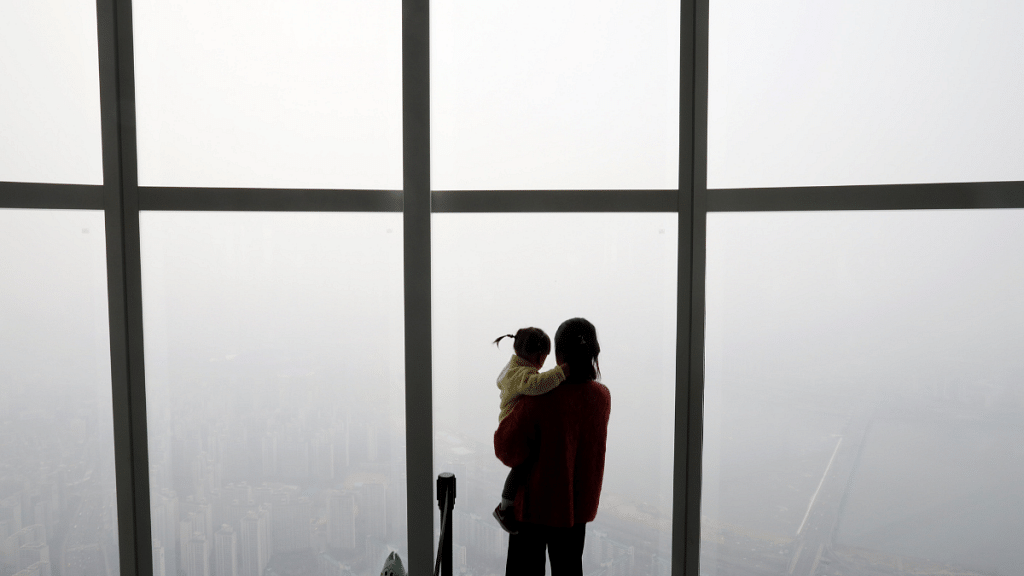 A woman holding her baby in her arms looks at a view of Seoul shrouded by fine dust during a polluted day in Seoul, South Korea, 6 March, 2019 | Reuters/Kim Hong-Ji
