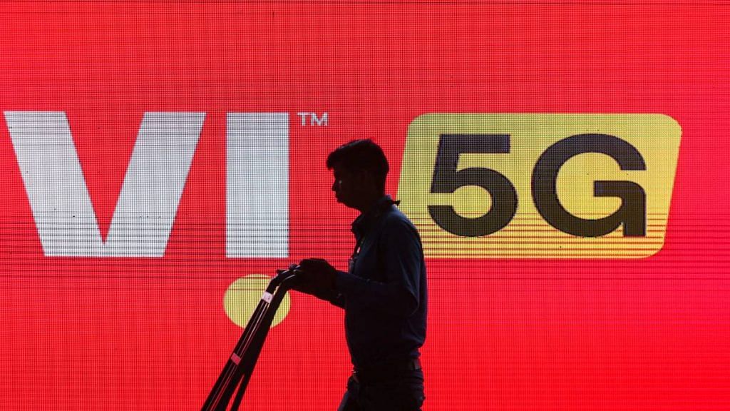 A man walks across the LED display board showing the logo of Vodafone-Idea | Representational image | Reuters file photo