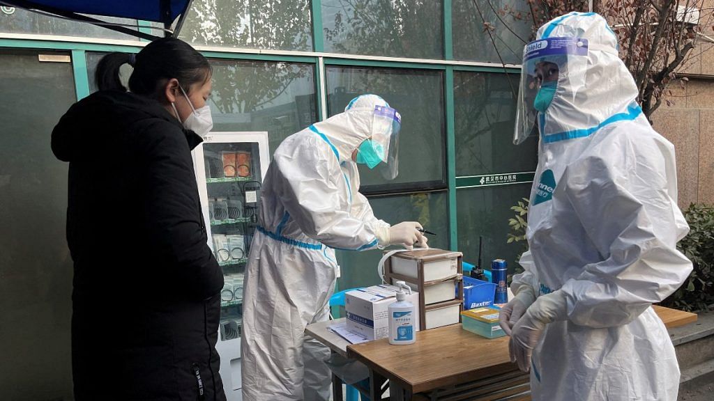 A medical worker in a protective suit registers information for a patient at the entrance to the fever clinic of the Central Hospital of Wuhan | Reuters file photo