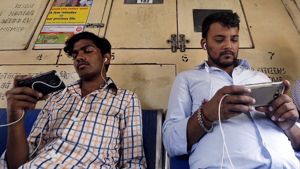 Commuters watch videos on their mobile phones as they travel in a suburban train in Mumbai | Representational image | Reuters