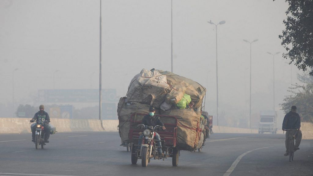 A man rides a motor tricycle, loaded with sacks of recyclables, amid dense smog in Lahore, Pakistan | File Photo: Reuters
