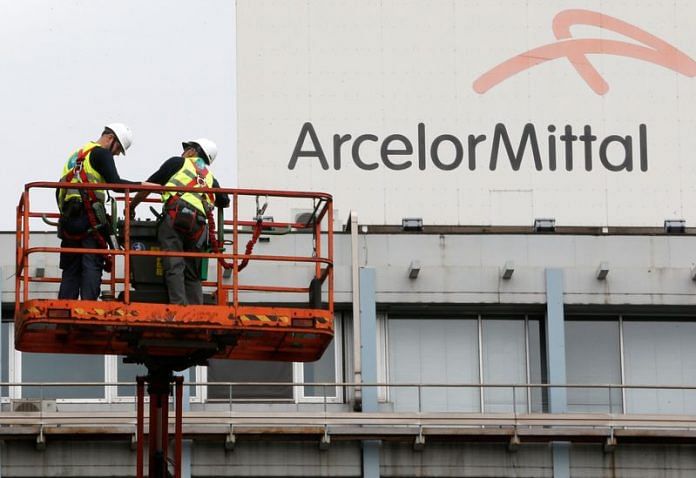 File photo of workers stand near the logo of ArcelorMittal, the world's largest producer of steel, at the steel plant in Ghent, Belgium | Photo: Reuters