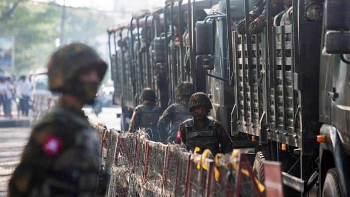 Soldiers stand next to military vehicles as people gather to protest against the military coup, in Yangon, Myanmar | File Photo: Reuters