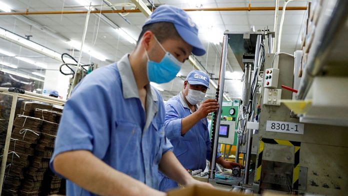 FILE PHOTO: Employees wearing masks work at a factory of the component maker SMC during a government organised tour of its facility following the outbreak of the coronavirus disease (COVID-19), in Beijing, China May 13, 2020. REUTERS/Thomas Peter