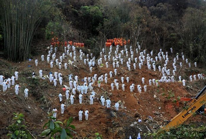 Rescue workers stand in a silent tribute at the site to mourn the victims of a China Eastern Airlines Boeing 737-800 plane, flight MU5735, that crashed in Wuzhou on 27 March 2022 | Photo: Reuters