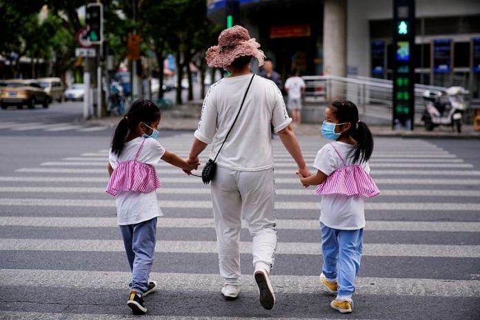 A mother walks with her twin daughters on a street in Shanghai, China 7 June, 2021 | Reuters/Aly Song