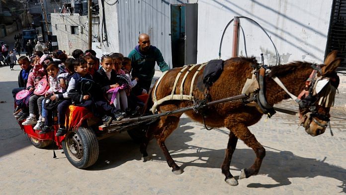 Palestinian man Loay Abu Sahloul offers to some students a low-cost donkey-cart ride to kindergarten in Khan Younis, southern Gaza Strip on 27 February 2023 | Photo: Reuters