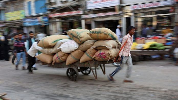Workers transport sacks that are loaded on a cart at a wholesale market in the old quarters of Delhi | File Photo: Reuters