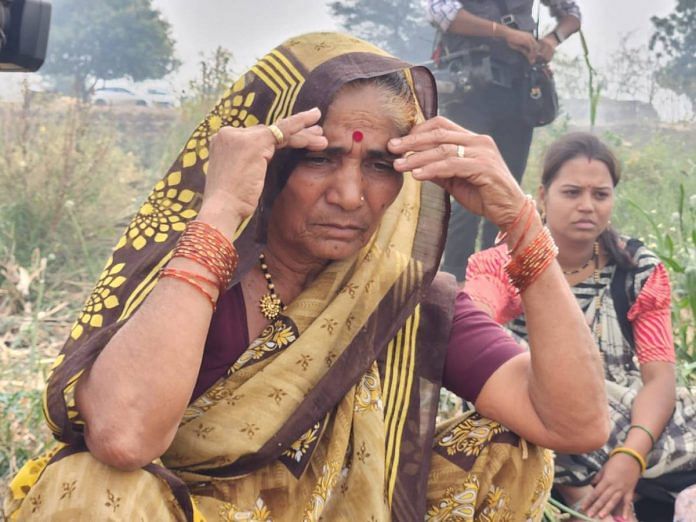 Mandabai, mother of Krishna Dongre, watches her son burn their onion crop on Monday. Photo- Purva Chitnis | ThePrint