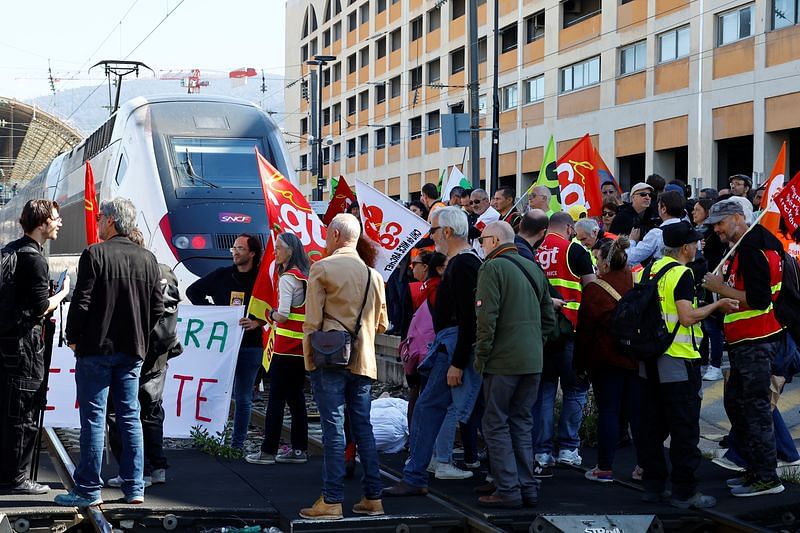 Workers on strike hold CGT labour union flags as they walk on railway tracks to block a TGV high speed train during a demonstration at the train station on the eve of the ninth day of national strike and protests, and after the pension reform was adopted as the French Parliament rejected two motions of no-confidence against the government, in Nice, France, on 22 March, 2023 | Reuters