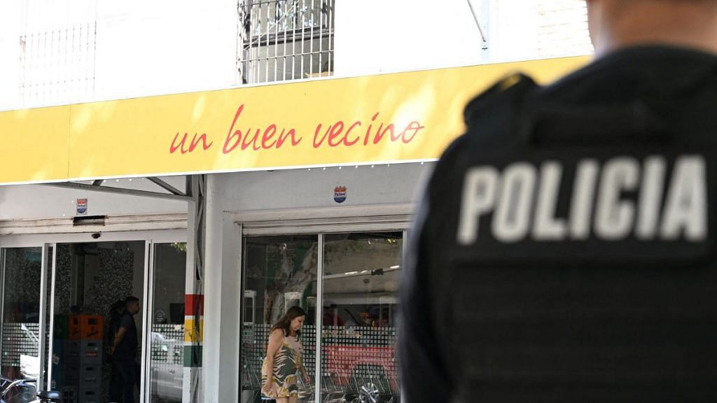 A police officer stands guard outside a supermarket that belongs to the family of Antonela Roccuzzo, wife of Argentine soccer star Lionel Messi, after after two people on motorcycles attacked it and left a threatening message for Messi and the city mayor, Pablo Javkin, according to local media, in Rosario, Argentina, 2 March 2023| Reuters/Luciano Bisbal