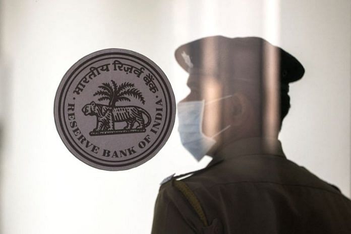 A security guard stands next to the logo of the Reserve Bank of India (RBI) inside its headquarters in Mumbai | File Photo: Reuters