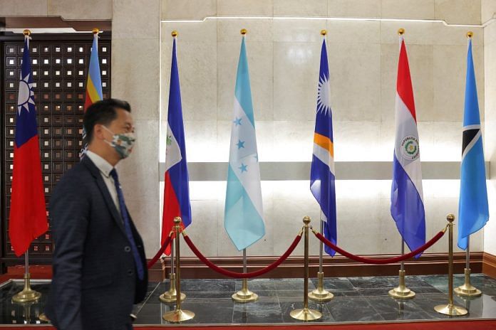 A man walks in front of flags of Honduras, Taiwan, and other countries, displayed at the Ministry of Foreign Affairs building in Taipei, on 23 March 2023 | Reuters