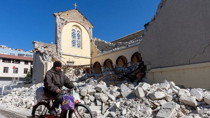 A man rides his bike along a collapsed Roman Catholic church in the aftermath of the deadly earthquake in Iskenderun, a coastal town of Hatay province, Turkey on 14 February | Photo: Reuters