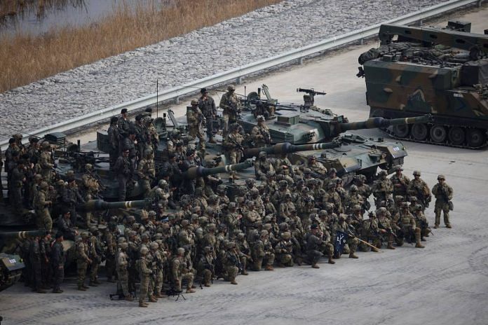 South Korean and US army soldiers pose for a group photo with South Korean army K1A1 tanks on 22 March 2023 | Reuters