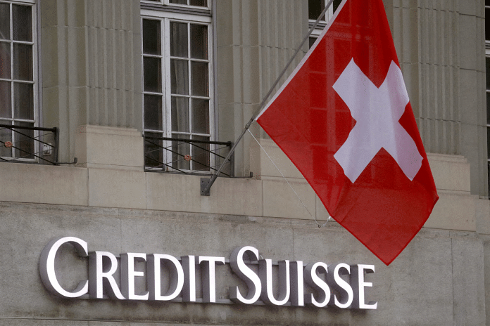Switzerland's national flag flies above a logo of Swiss bank Credit Suisse in front of a branch office in Bern, Switzerland | 29 November 2022 | Reuters/Arnd Wiegmann