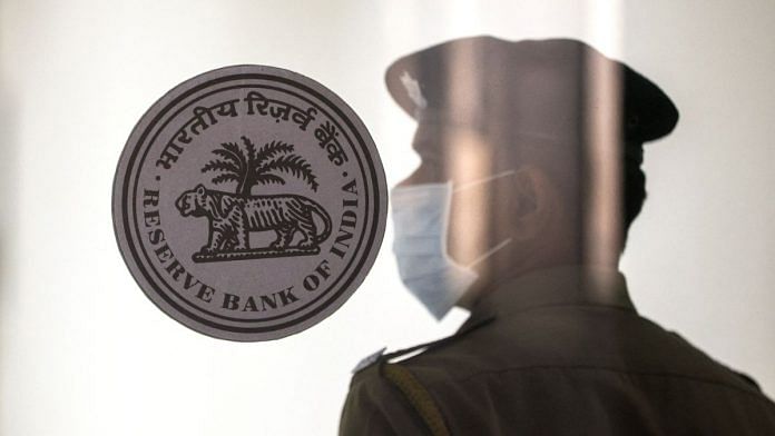 File photo of a security guard standing next to the logo of the Reserve Bank of India (RBI) inside its headquarters in Mumbai, India, February 8, 2023 | Reuters