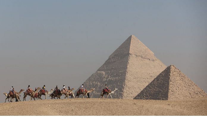 Tourists ride camels in front of the Great Pyramids plateau in Giza, Egypt on 11 December, 2022 | Reuters