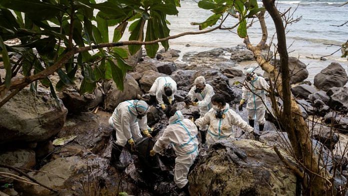 Volunteers dressed in personal protective equipment clean up the oil spill from the sunken fuel tanker MT Princess Empress, on the shore of Pola, in Oriental Mindoro province, Philippines on 7 March, 2023 | Reuters