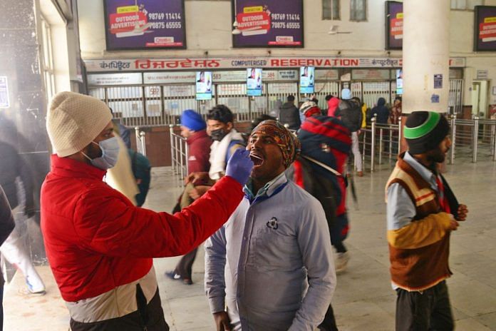 A healthcare worker collects an oral swab sample from a passenger at a railway station in Jalandhar | ANI file photo