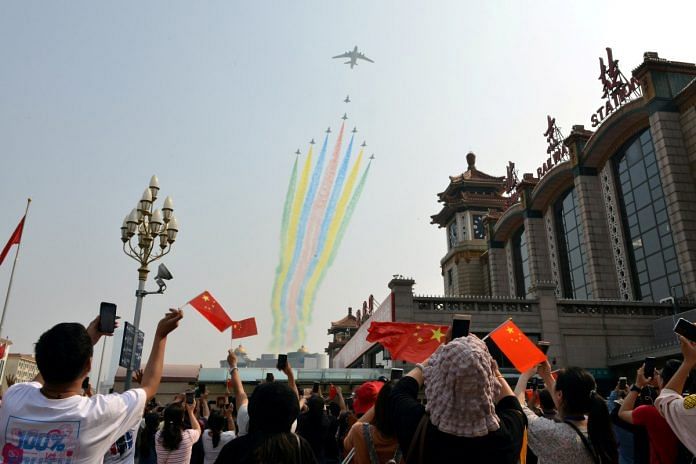 People hold their mobile phones and Chinese flags as military aircraft fly in formation during the military parade marking the 70th founding anniversary of the People's Republic of China in Beijing | Reuters file photo