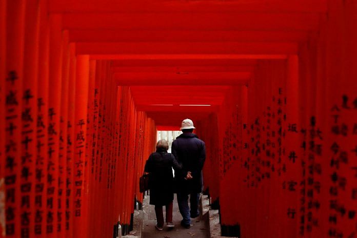 An elderly couple walks through red-coloured wooden torii gates at a shrine, amid the Covid-19 outbreak, in Tokyo, Japan | File Photo: Reuters