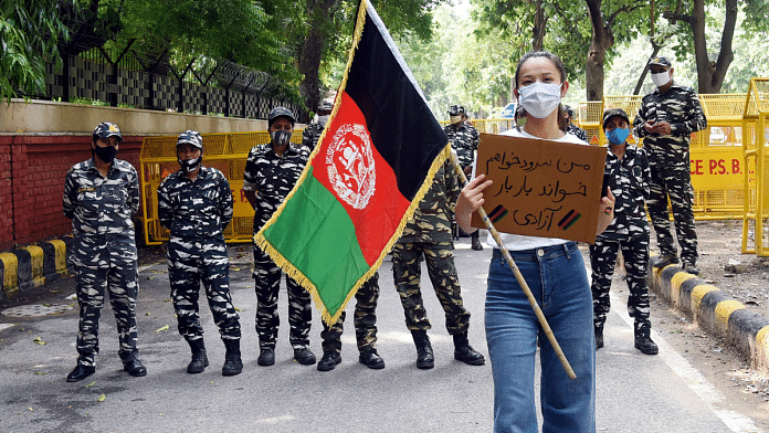 File photo of a woman holding an Afghan national flag during a protest in Delhi against the takeover of Afghanistan by Taliban | ANI