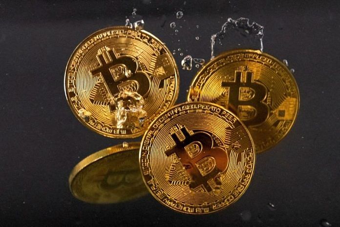 Souvenir tokens representing cryptocurrency Bitcoin plunge into water in this illustration | Reuters