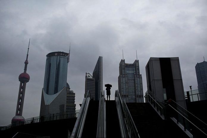 A woman holds an umbrella on an escalator in the financial district of Pudong, Shanghai | File Photo: Reuters