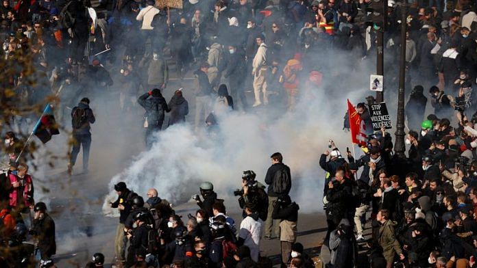 People react amid tear gas during clashes at a demonstration as protester gather on Place de la Bastille as part of the 12th day of nationwide strikes and protests against French government's pension reform, in Paris on 13 April, 2023 | Reuters