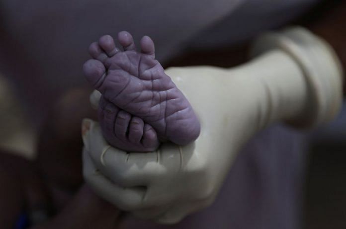 A nurse holds the feet of a newborn baby | Reuters