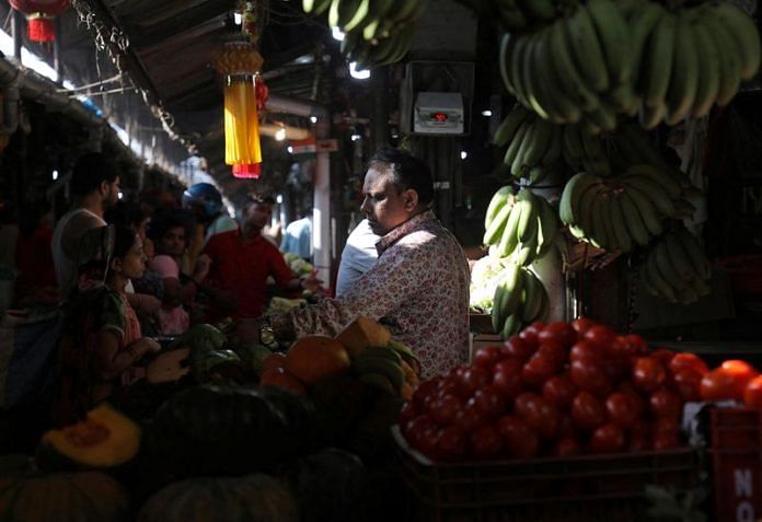 A fruit vendor tends to customers at a fruit and vegetable wholesale market in Mumbai