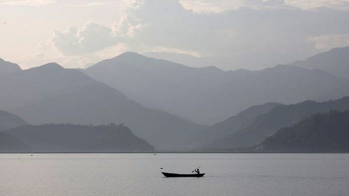 The Annapurna mountain range is seen in the background as a man paddles through Phewa Tal lake in Pokhara | File Photo: Reuters